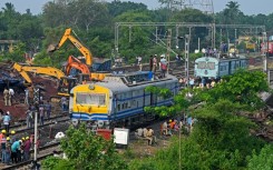 Police and workers inspect damaged carriages and tracks after a train disaster in the eastern state of Odisha killed at least 288 people