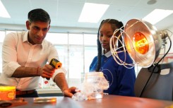 British Prime Minister Rishi Sunak takes part in a science experiment as he visits the Friendship Technology Preparatory High School in Washington