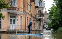 A local resident uses a paddle board during an evacuation from a flooded area in Kherson 