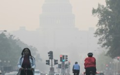 People commute under a blanket of haze partially obscuring the US Capitol in Washington