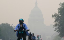 A cyclist rides under a blanket of haze partially obscuring the US Capitol in Washington, DC, on June 8, 2023