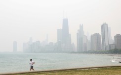 A jogger runs along the shoreline of Lake Michigan with heavy smoke from the Canadian wildfires covering the city of Chicago in a thick haze