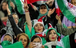 Women football fans wave national flags and cheer during a friendly match between Iran and Kenya in Tehran in March
