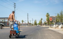 A person transports a water jug through a neighborhood in Phoenix, Arizona on July 14, 2023