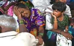Relatives of those killed in a landslide weep in a house at Irshalwadi village in India's Maharashtra state
