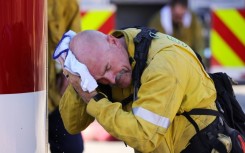 A San Bernardino County firefighter wipes his head as the Oak Fire burns near Fontana, California