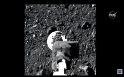 The robotic arm of NASA's OSIRIS-REx spacecraft makes contact with the surface of asteroid Bennu, as seen on an October 2020 video broadcast