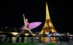 US surfer and adventurer Alison Teal jumps with her surfboard next to the Seine River in front of the Eiffel Tower in Paris.