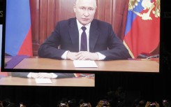 Delegates take pictures of the screen as Russian President Vladimir Putin delivers his remarks virtually during the 2023 BRICS Summit. AFP/Marco Longari 