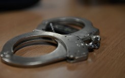 File: A set of handcuffs lying on a desk. Wikimedia Commons/Airman 1st Class Gustavo Castillo