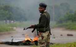 A soldier stands before a burning barricade during protests in Harare, Zimbabwe.