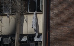 A blanket hanging out of a window that residents used to climb out of the building at the scene of a fire in Johannesburg. AFP/Michele Spatari 
