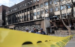 Police officers stand at the scene of the Joburg building fire. AFP/Luca Sola