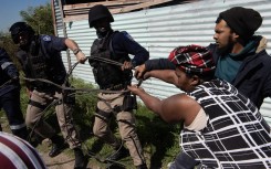 Members of the Cape Town Metro Police try to pull away a piece of illegally connected electricity wire from residents of an informal settlement called Oasis Farm, near Cape Town, on September 13, 2023.