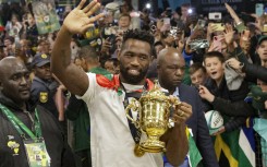 South Africa's flanker and captain Siya Kolisi waves at supporters as he holds the Webb Ellis Cup upon the South African rugby team's arrival at the OR Tambo International airport in Ekurhuleni on October 31, 2023, after they won the France 2023 Rugby World Cup final match against New Zealand. 