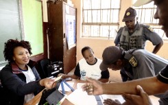 An IEC official gives back an identity document to a South African man after registering him as a voter. AFP/Luca Sola