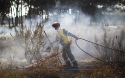 A firefighter doses a smouldering fire to prevent spreading on the outskirts of Scarborough. AFP/Gianluigi Guercia