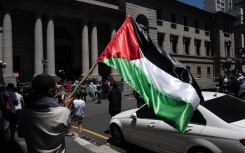 A man holds a Palestinian flag as they take part in a pro-Palestinian demonstration outside the High Court in Cape Town on January 11, 2024. Dozens of people took to the streets in Cape Town on on January 11, 2024 in one of several demonstrations planned across South Africa in support of the government’s landmark "genocide" case against Israel. 