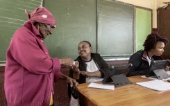 A woman gives her identity document to an IEC official to be registered as a voter. AFP/Luca Sola