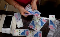 A woman counts money at the Central Market in Buenos Aires. AFP/Luis Robayo