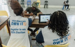 IEC officials assist a voter to be registered at a voting station. AFP/Rajesh Jantilal