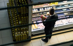 A customer takes a close look at prices while shopping in a grocery store. AFP/Jekesai Njikizana