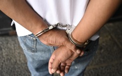 File: An alleged member of a human trafficking network is escorted by police after being arrested. AFP/Johan Ordonez