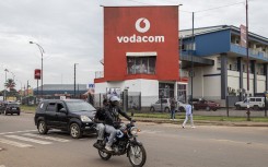 File: Vehicles drive past a Vodacom building in Lubumbashi. AFP/Patrick Meinhardt