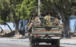 Somalian soldiers drive on the back of a military vehicle in a street near a hotel in Mogadishu. AFP/Hassan Ali ELMI