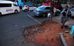 Traffic and pedestrians navigate a hole in the road in Johannesburg. Leon Sadiki/Bloomberg via Getty Images