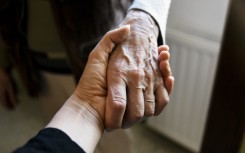 A young woman holds the hand of an old woman. AFP/Magali Cohen/Hans Lucas via AFP