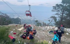 rescue teams conducting a rescue operation and helping injured people after a cable car cabin crashed into a fallen cable pole. AFP/DHA