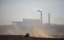 File: A farmer works with its tractor in front of the Kusile Power Station located in eMalahleni. AFP/Wikus de Wet