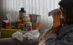 File: A woman lying in an armchair, coughing and covering her mouth with tissues. Artur Widak/NurPhoto via AFP