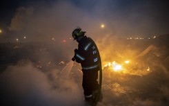 File: Members of the City of Cape Town Fire and Rescue Services extinguish a fire. AFP