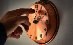 File: A man changing time on a clock. Lorenzo Di Cola/NurPhoto via AFP
