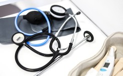 medical instruments including a stethoscope and thermometer as they lie on a table in a doctor's office. AFP/Charly Triballeau
