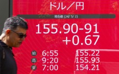 A man walks in front of an electronic board displaying the exchange rate for the Japanese yen against the US dollar. AFP/Kazuhiro Nogi