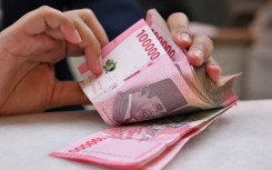 A clerk poses with Indonesian rupiah banknotes at a money changer in Jakarta. AFP/Adek Berry