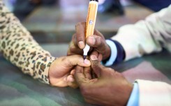 An IEC official marks a voter with indelible ink at a polling station. AFP/Zinyange Auntony