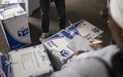 An election observer writes down notes as an IEC official tapes ballot boxes shut. AFP/Emmanuel Croset