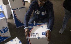 An IEC official tapes a ballot box shut in front of election observers. AFP/Emmanuel Croset