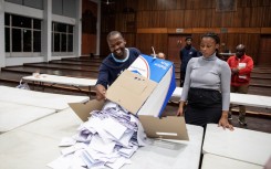 IEC) officials empty a ballot box during the vote counting process. AFP/Gianluigi Guercia