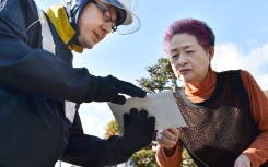 File: A postal delivery person hands an envelope containing a notification card for the My Number common identification system to a woman in Sunagawa. AFP/Kenji Shimizu/Yomiuri