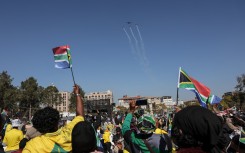South Africans fly flags as they look at a flypast during President Cyril Ramaphosa's inauguration. AFP/Phill Magakoe