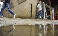 File: People pass a wall with graffiti as traders stand outside a shop in Harare. AFP