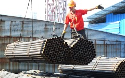 File: A worker directs a crane to lift steel products to be exported at a steel market. Yi chang/Imaginechina via AFP