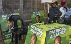 Patriotic Alliance (PA) supporters sit outside the Jan Hofmeyer Recreation Centre polling station in Brixton, Johannesburg on May 29, 2024, during South Africa’s general election.