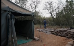 A police officer stands near the entrance to a farm where they detained ninety five Libyan nationals for receiving training at what authorities suspect to be a secret military camp. AFP/Phill Magakoe