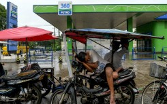 A man sleeps on his motorcycle as motorists queue to fill their vehicles at a petrol station in Yangon. AFP